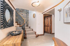 A staircase with a stone wall, a wooden door, and a wall-mounted mirror.