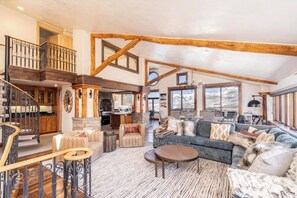 A spacious living area with a staircase, a fireplace, and a large window offering a view.