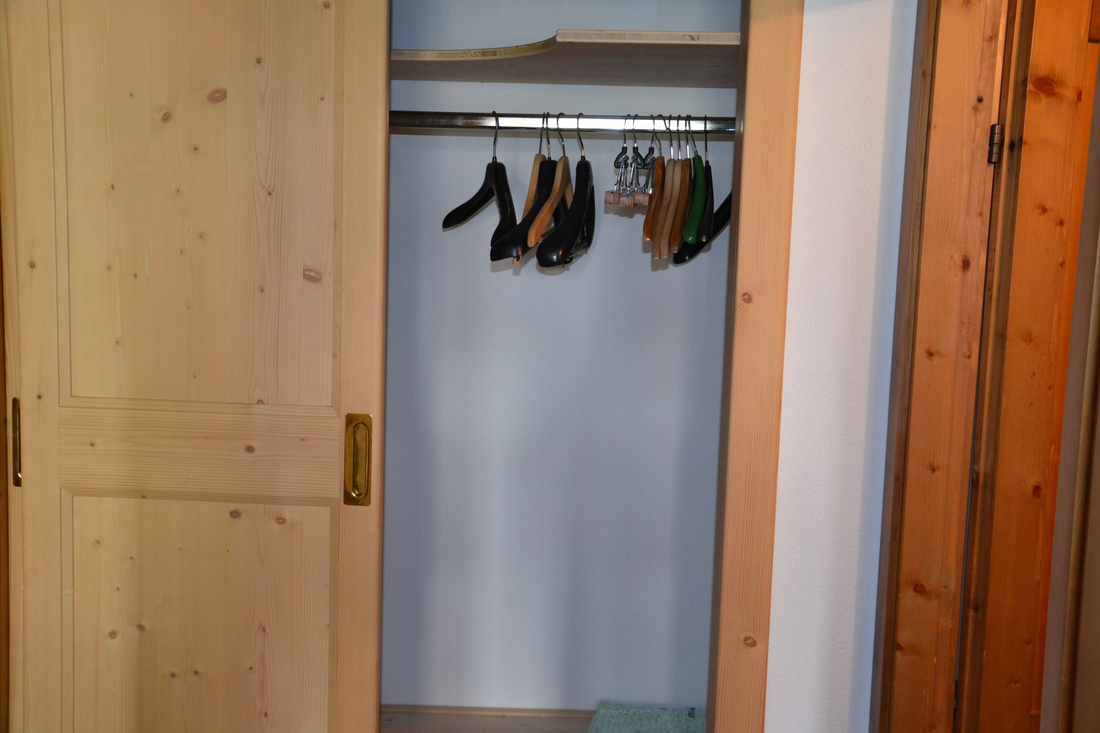 A wooden closet with a hanging rod for shoes.