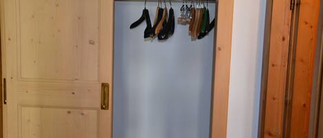 A wooden closet with a hanging rod for shoes.