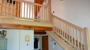 A wooden staircase with a wooden railing leading to an upper level. There is a door on the right side of the staircase, and a clock on the wall to the left. - Sasso Rosso Apartment with Alps View (Folgarida)