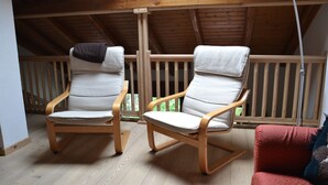 Two rocking chairs with cushions, a wooden floor, and a wooden ceiling. - Sasso Rosso Apartment with Alps View (Folgarida)