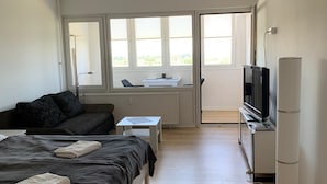 A modern hotel room with a bed, a desk, a television, and a view of the outdoors. - Vacation Apartment K1213 with a View of the Baltic Sea (Schönberg OT Holm)