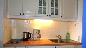 A kitchen with white cabinets, a wooden countertop, a coffee maker, a kettle, and a sink. - Vacation Apartment K1213 with a View of the Baltic Sea (Schönberg OT Holm)