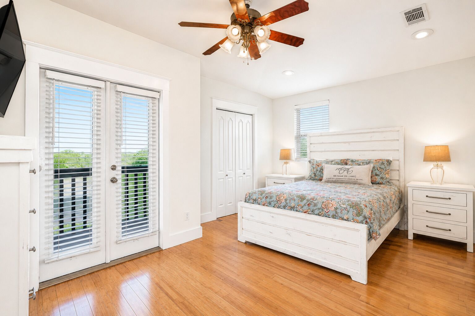 A bedroom with a bed, a ceiling fan, a nightstand, and a window.
