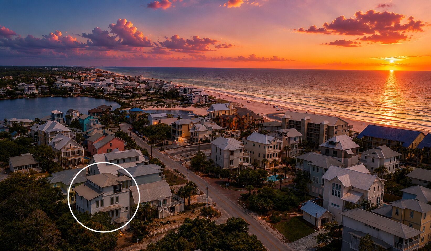 A coastal residential area with houses, a beach, and a sunset.