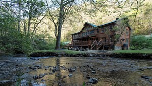 Une cabane en rondins dotée d’une terrasse donnant sur un ruisseau.