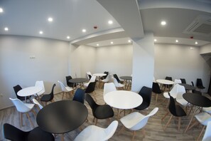 A conference room with multiple tables and chairs, white walls, and recessed ceiling lighting. - Peloton Inn (Katerini)