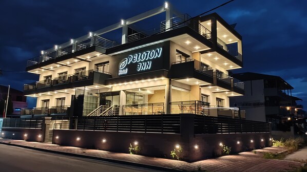 A modern hotel with a prominent sign, multiple balconies, and a well-lit facade. - Peloton Inn (Katerini)