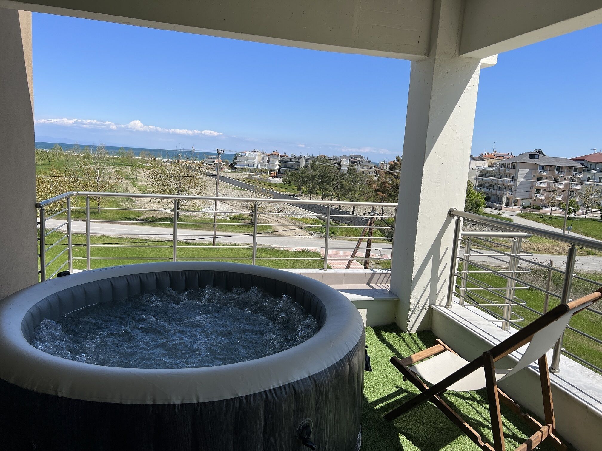 Un jacuzzi sur un balcon avec vue sur un quartier résidentiel et une route.