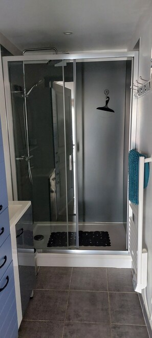 A modern bathroom with a glass-enclosed shower, a white sink, and a towel rack.