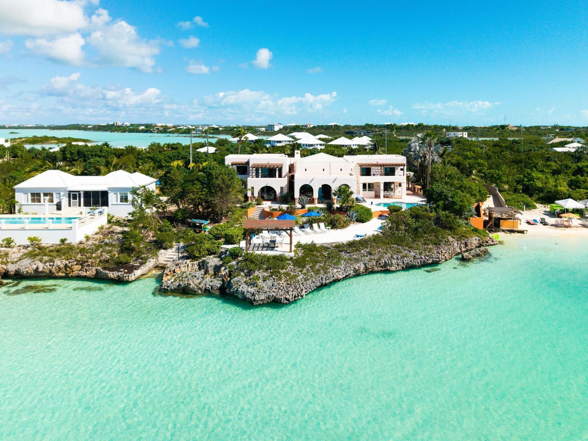 A coastal property with multiple buildings, a swimming pool, and a beach area.