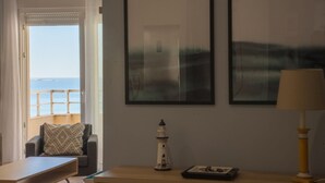 Una habitación con vista al mar, una mesita con una lámpara y un cuadro enmarcado en la pared.