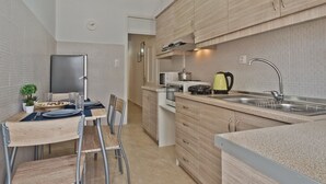 Een moderne keuken met houten kastjes, een spoelbak en een eethoek met stoelen en een tafel gedekt voor twee personen.