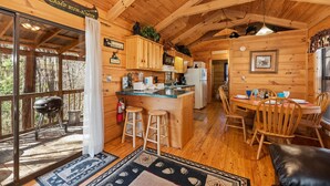 A cabin interior with a kitchen, dining area, and a deck. - Forever Mine: A Romantic Escape for Two (Gatlinburg)