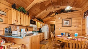 A wooden cabin interior with a kitchen, dining area, and bar stools. - Forever Mine: A Romantic Escape for Two (Gatlinburg)