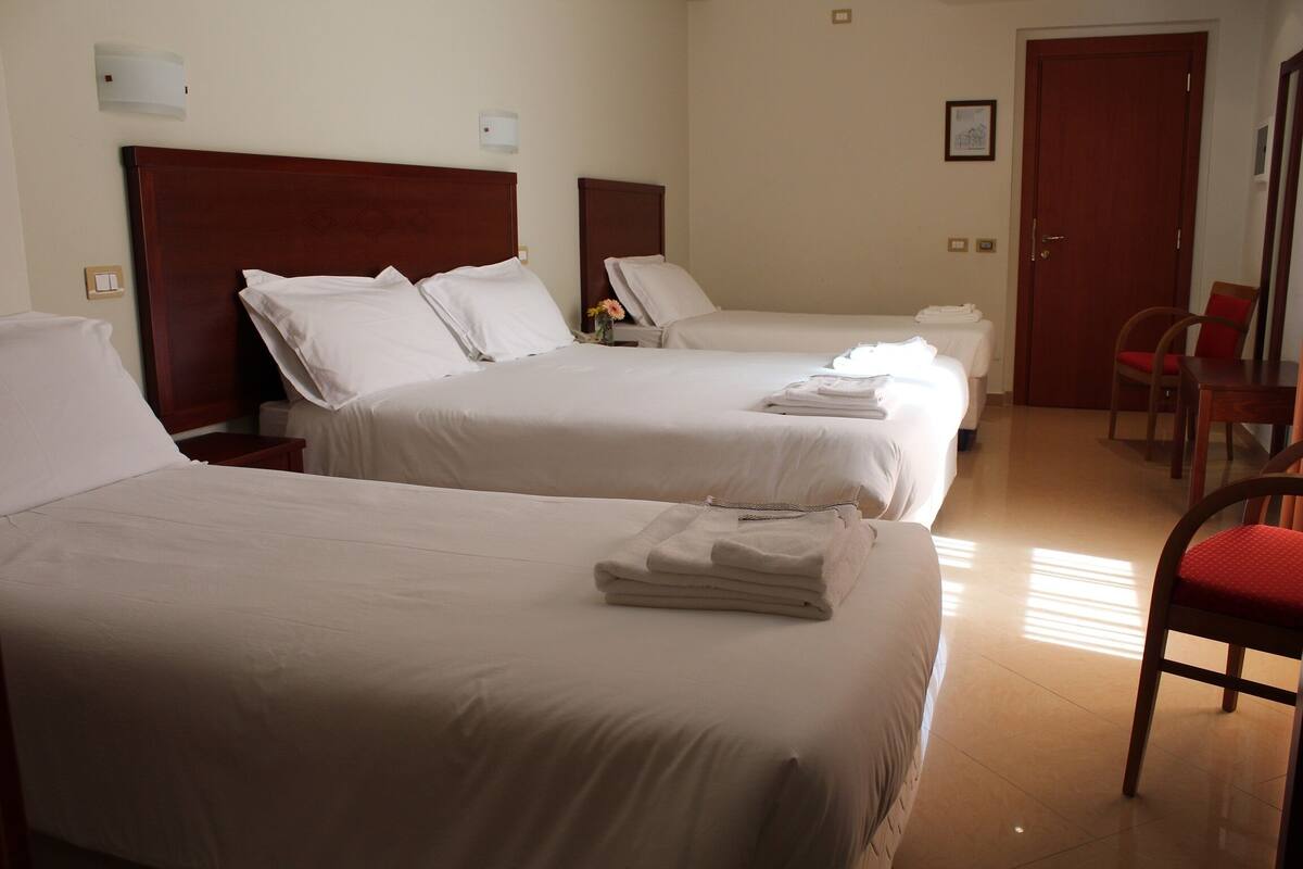A hotel room with two beds, a wooden headboard, a chair, and a door.