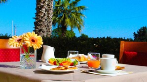 A table set for breakfast with plates of food, glasses of juice, and a vase of flowers. - Città Della Notte (Melilli)