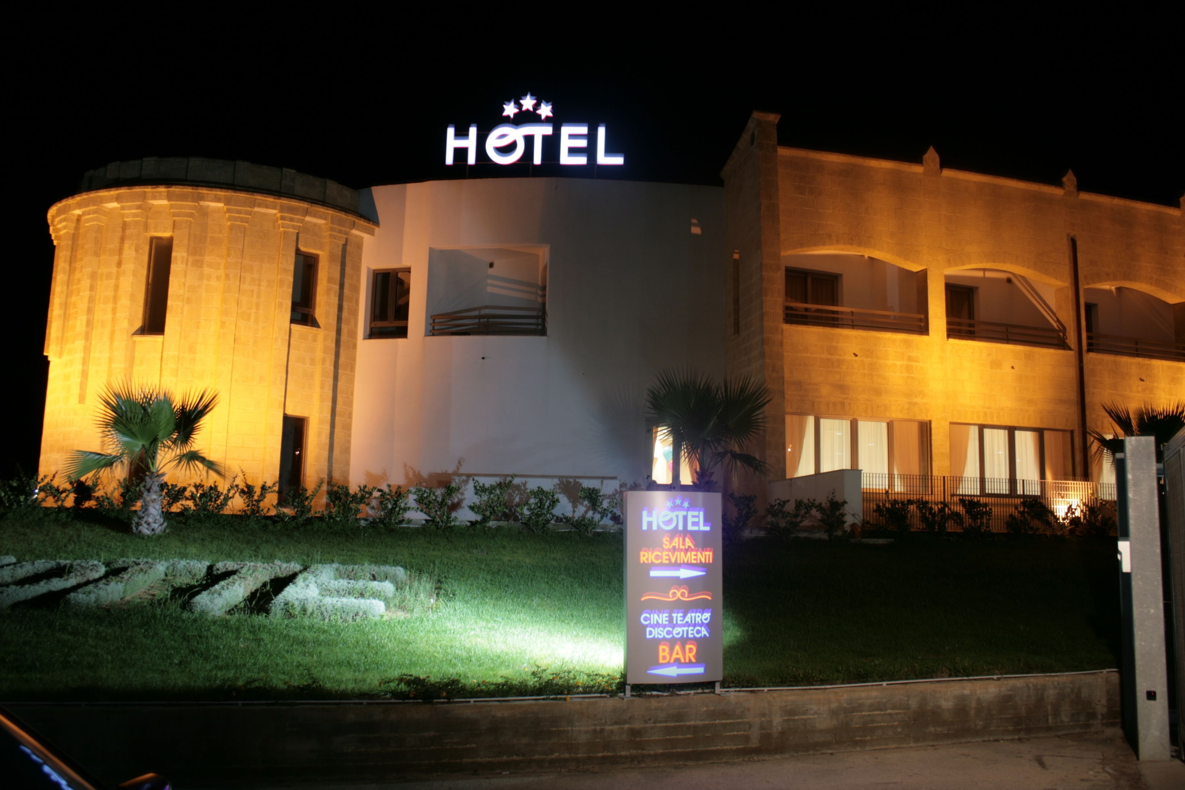 Un hotel con un cartello ben visibile con la scritta 'HOTEL', una reception e una insegna che pubblicizza un bar, un cinema e un ristorante.