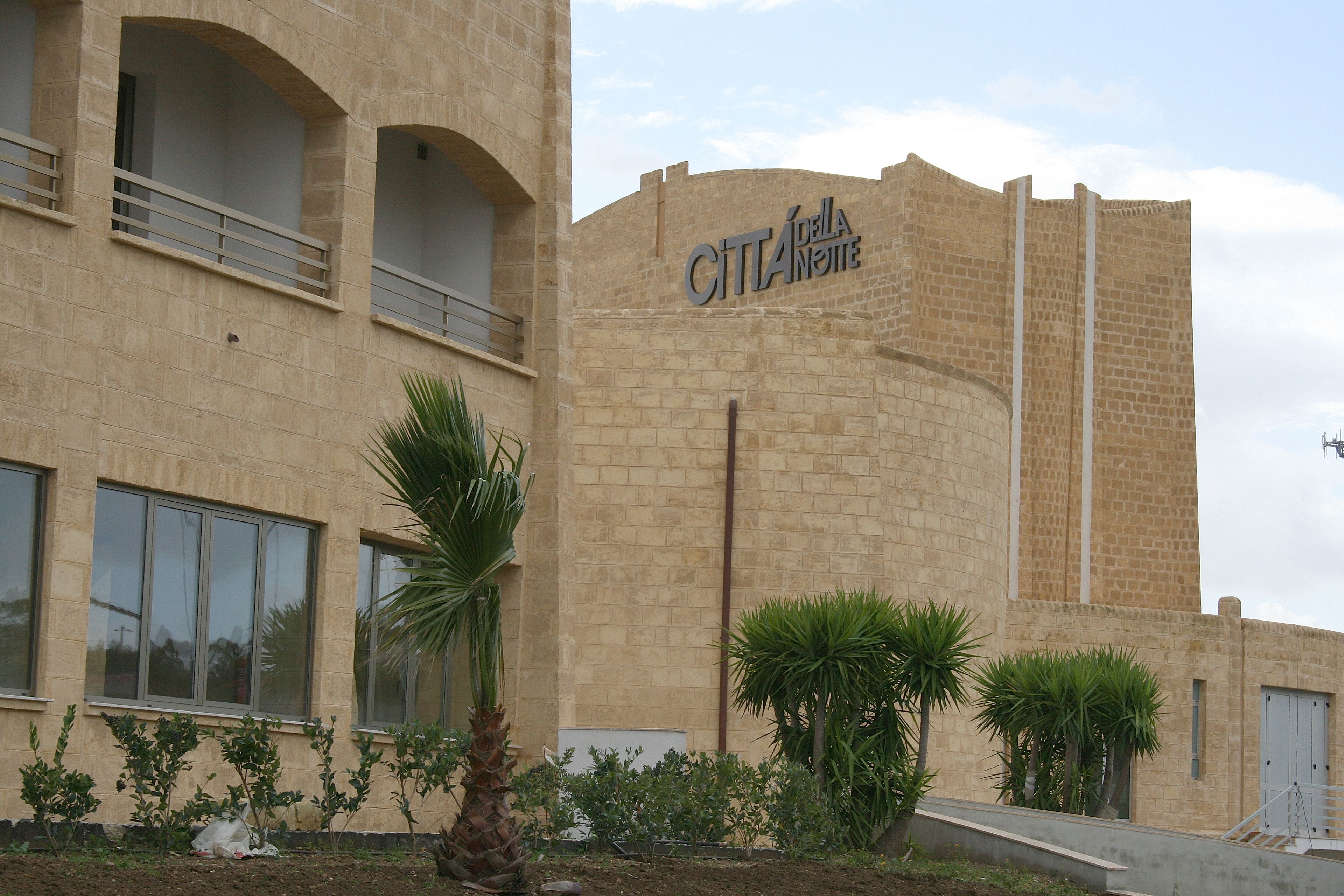 A building with a stone facade and a sign reading "CITTA DELLA NOITE".