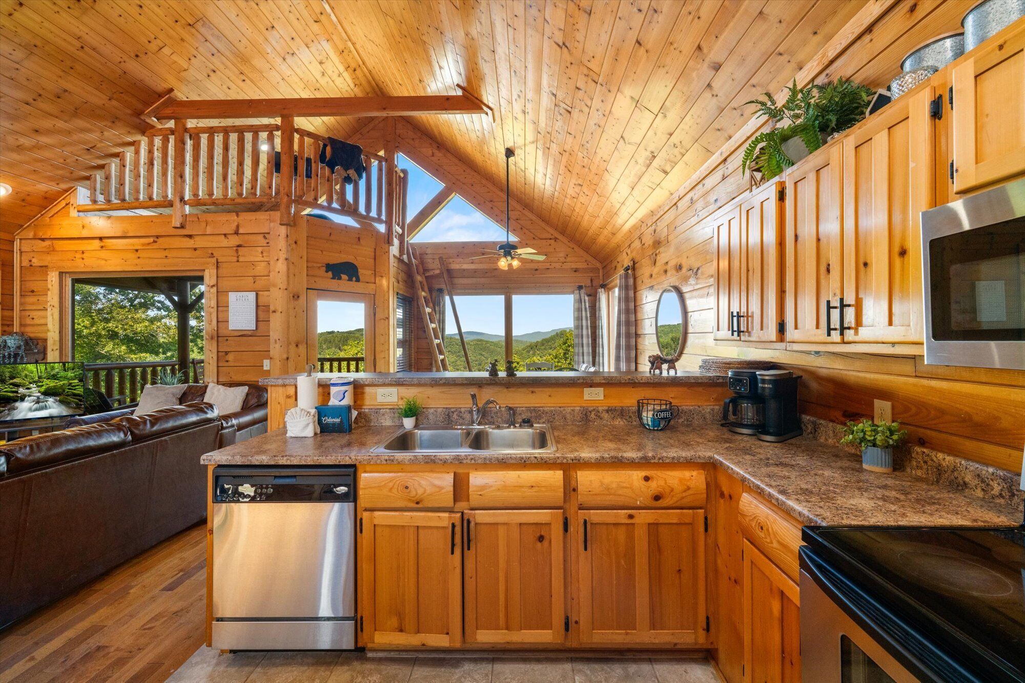 A wooden cabin with a kitchen featuring a stainless steel dishwasher, a coffee maker, and a large oven.