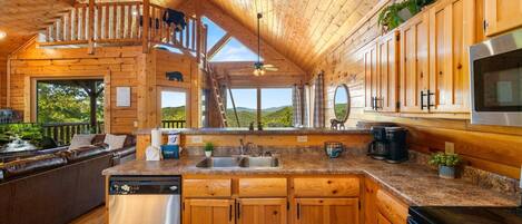A wooden cabin with a kitchen featuring a stainless steel dishwasher, a coffee maker, and a large oven.