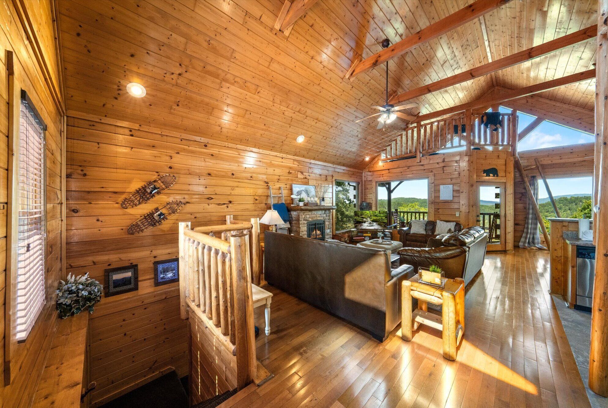 Une cabane en bois spacieuse, dotée d’un plafond haut, d’une cheminée, d’un coin repas et d’un balcon offrant une vue panoramique.