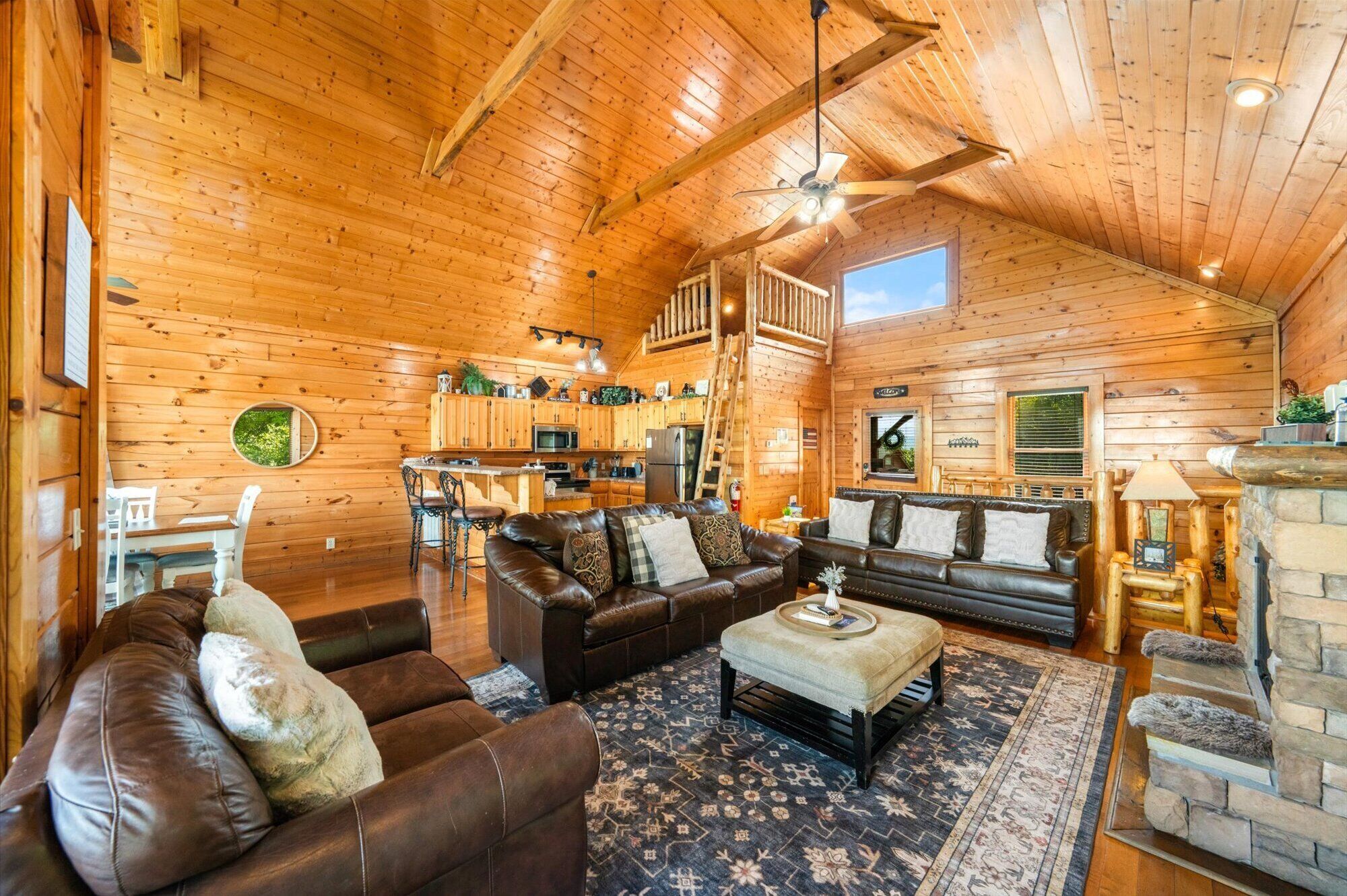 A spacious log cabin interior with a living room, dining area, and kitchen.