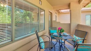 Un balcon avec une table, des chaises et un pot de fleurs.