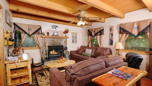 A cozy living room with a fireplace, wooden furniture, and a ceiling fan. - Smoky Mountain High: Where the Mountains Lift You (Gatlinburg)