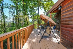 Relax on the deck surrounded by lush greenery and trees, with a swing chair and outdoor furniture.