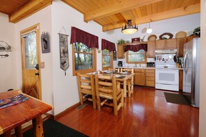 Enjoy meals in this warm dining area with a wooden table and chairs, surrounded by large windows.