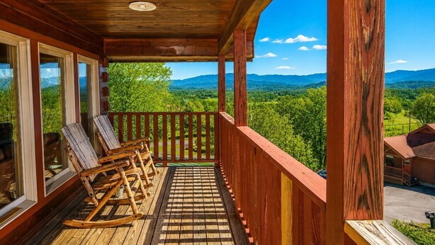 A wooden porch with rocking chairs and a view of the mountains. - Deer Lodge: Putt, Play & Take in the Views (Pigeon Forge)