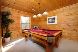 Relax in a spacious room with a pool table, framed artwork, and a potted plant.