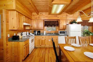 Enjoy cooking in this well-equipped kitchen with a central island, stove, sink, microwave, and refrigerator.