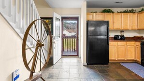 Una cocina con armarios de madera, un refrigerador negro y una gran rueda de madera.