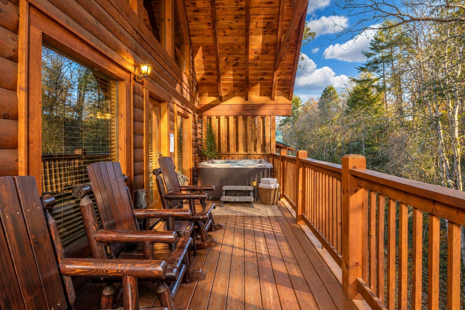 Een houten terras met een jacuzzi, houten stoelen en uitzicht op bomen.