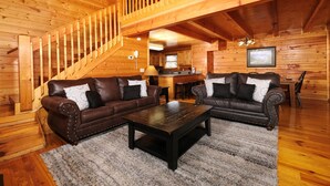 Un interior de madera con dos sofás de cuero, una mesa de centro y una escalera.