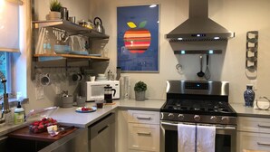 Eine moderne Küche mit Edelstahlgeräten, einer Mikrowelle, einer Kaffeemaschine und einem Herd. Es gibt ein Spülbecken, einen Geschirrständer und ein Fenster mit Blick.