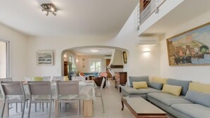 Un amplio salón con una mesa de comedor, sillas, un sofá y un cuadro en la pared.
