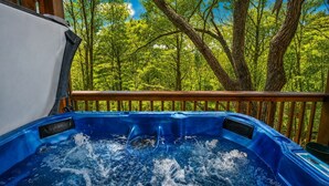 A hot tub on a wooden deck with a view of trees. - Raccoons' Rest: Kick Back in the Smokies (Pigeon Forge)