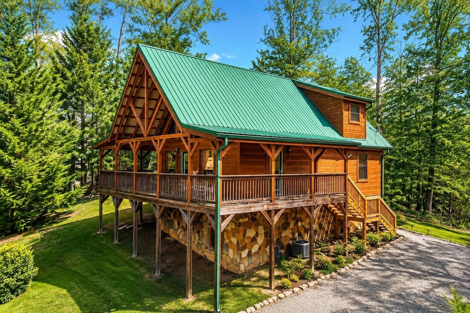 A wooden cabin with a green roof, a stone foundation, and a wooden deck.