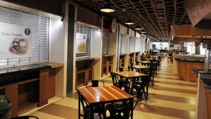 A restaurant with wooden tables and chairs, a tiled floor, and a patterned ceiling. - Ten Eleven Living Point (Bandung)