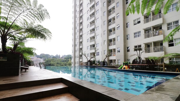 A swimming pool with steps leading up to it, surrounded by a high-rise building with balconies. - Ten Eleven Living Point (Bandung)