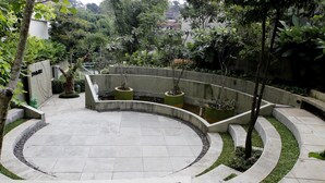A circular courtyard with a central water feature, surrounded by planters and trees. - Ten Eleven Living Point (Bandung)
