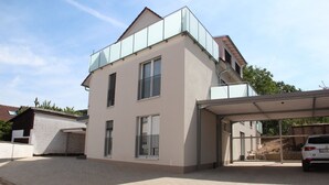 Una casa moderna a due piani con garage coperto e un'auto parcheggiata all'interno.