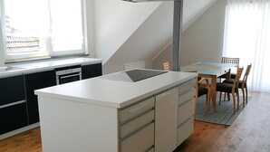 Una cucina moderna con isola centrale, pavimento in legno e zona pranzo con sedie.
