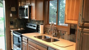 Una cocina moderna con armarios de madera, electrodomésticos de acero inoxidable y un amplio ventanal.