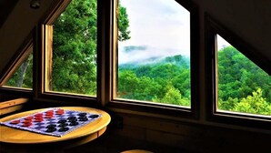Una habitación con tres ventanas amplias que dan a un paisaje boscoso.