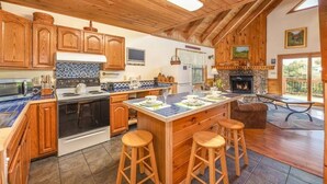Una cocina con armarios de madera, una estufa y un comedor con taburetes.